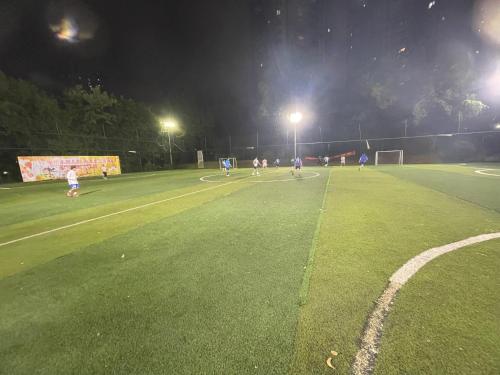 a group of people playing soccer on a soccer field at night at 哲帆民宿花园洋房江与城店 in Chongqing