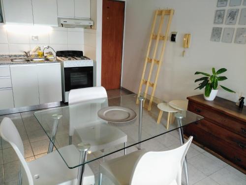 a kitchen with a glass table and white chairs at BV ILLIA TERMINAL DE OMNIBUS in Cordoba