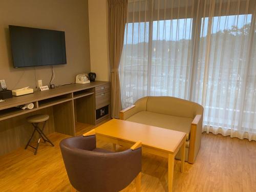 a living room with a table and a television and a chair at Ayagawasou in Miyazaki