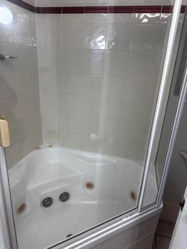 a bathroom with a shower with a white tub at Kings Row Apartments in Caloundra