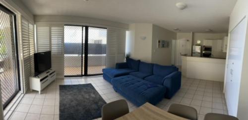 a living room with a blue couch and a tv at Kings Row Apartments in Caloundra