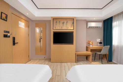 a hotel room with a bed and a tv on a wall at Yi Nuo Hotel Guangzhou in Guangzhou