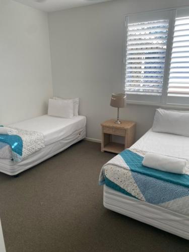 a bedroom with two beds and a window at Kings Row Apartments in Caloundra