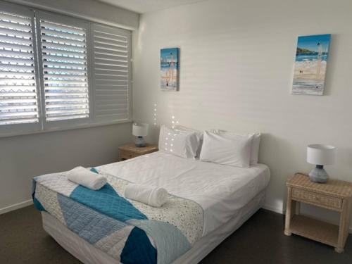 a bedroom with a bed with white sheets and pillows at Kings Row Apartments in Caloundra