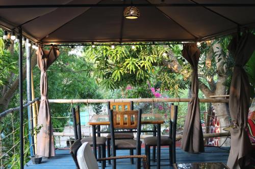 a porch with chairs and a table and trees at Restaurante y Ecohostal Casa Loma in Chorrera