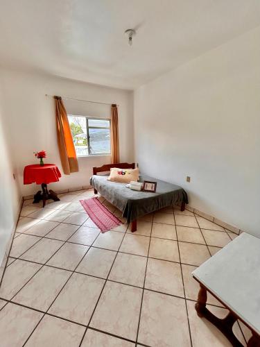 a living room with a bed and a table at Quarto confortável em Imbituba in Imbituba