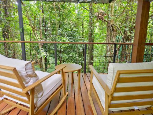 a porch with two chairs and a table at Secret Bungalows Lechu in Chachagua