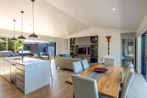 a kitchen and living room with a table and chairs at The Golden Pohutukawa - Beach House in Blackpool