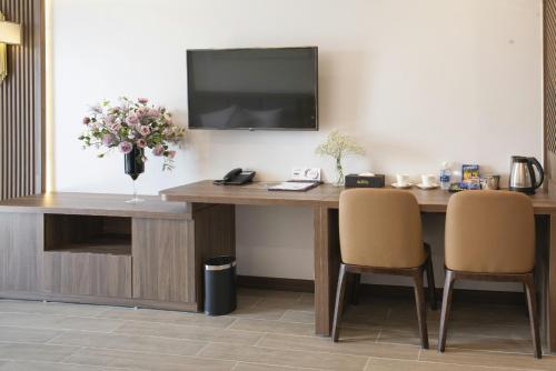 a desk with two chairs and a television on a wall at ZEN RIVERSIDE HOTEL & RESIDENCES in Hai Phong