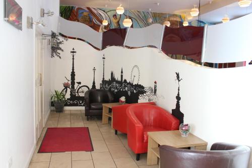 a restaurant with red chairs and a mirror on the wall at Desalis Hotel London Stansted in Elsenham