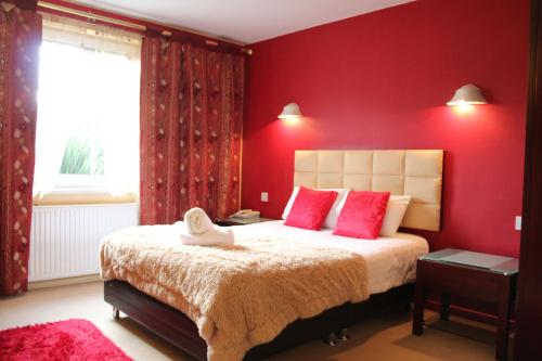 a bedroom with red walls and a bed with pink pillows at Desalis Hotel London Stansted in Elsenham