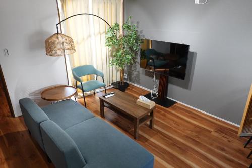 a living room with a blue couch and a tv at Hook House Stay Kanazawa in Kanazawa