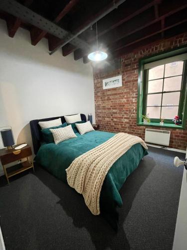 a bedroom with a green bed and a brick wall at Melbourne Riverside Retreat in Melbourne