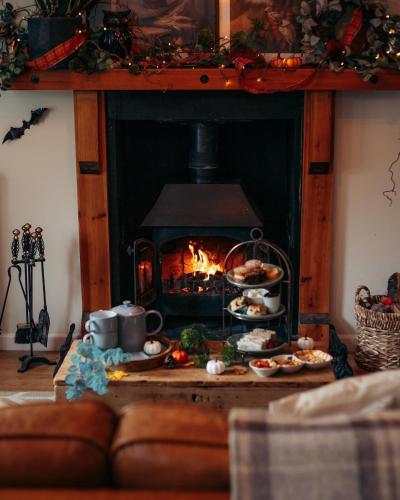a living room with a fireplace with food in front of it at 4 Walkers Cottage - Cosy, dog friendly with private unique BBQ hut! in Pont Sticill
