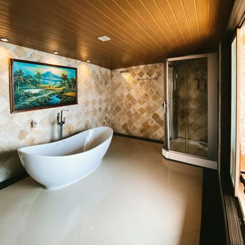 a bathroom with a large white tub and a shower at Sylvia Beach Villa in Labuan Bajo