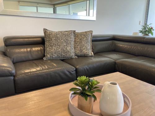 a brown leather couch in a living room with a vase at Waves Maroochy River in Maroochydore