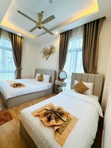 a bedroom with two beds and a ceiling fan at Hạ Tím Villa in Xuan An