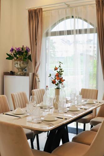 a dining room table with chairs and a large window at Hạ Tím Villa in Xuan An