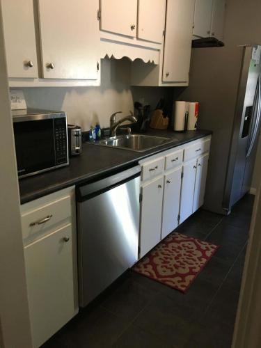 a kitchen with white cabinets and a sink and a microwave at Enchanting Forestwood Retreat in Mobile