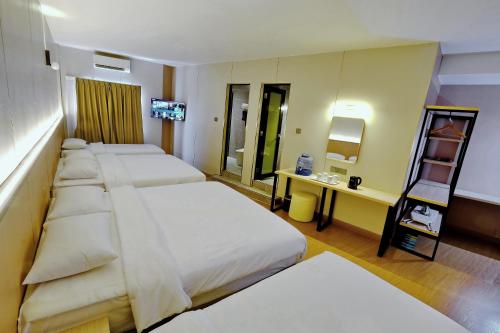 a hotel room with four beds and a desk at Ming Paragon Hotel in Kuala Terengganu