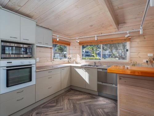 a kitchen with white appliances and a wooden ceiling at Waterfront Paradise - Pauanui Holiday Home in Pauanui