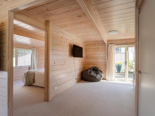 a wooden room with a bed and a television in it at Waterfront Paradise - Pauanui Holiday Home in Pauanui