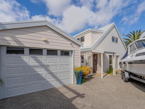 a garage with a car parked next to a house at Waterfront Paradise - Pauanui Holiday Home in Pauanui