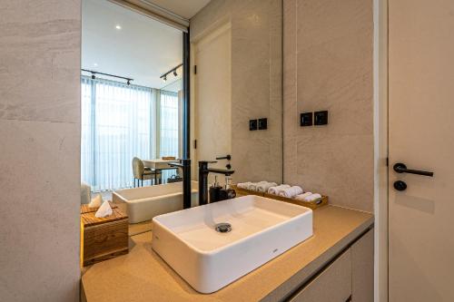 Un baño con un lavabo blanco y un espejo. en Oasis Villa 8 by Betterplace, en Canggu