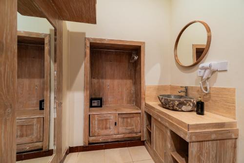 ウブドにあるPondok Wana Ubudの木製の洗面台と鏡のあるバスルーム