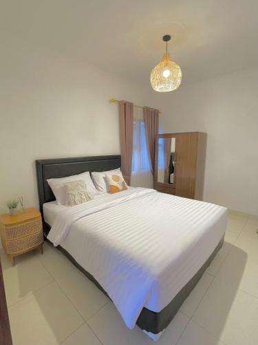 a bedroom with a large white bed with a chandelier at Kataleya Villa, Punclut 4BR in Bongkar 2