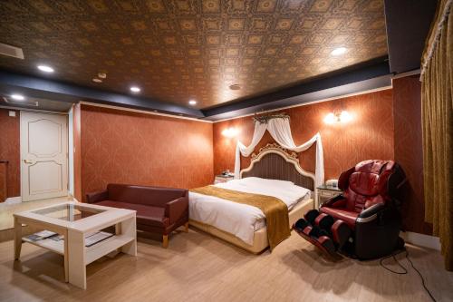 a bedroom with a bed and a chair and a table at ホテルパティオ in Suwa