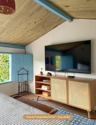 a bedroom with a large flat screen tv on the wall at Minha Casa em Caraíva, no centro da vila in Caraíva