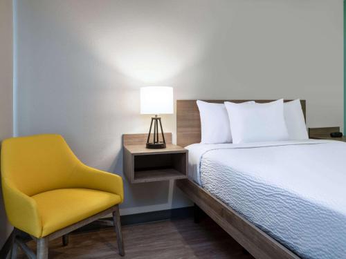 a bedroom with a bed and a yellow chair at ECHO Suites Extended Stay by Wyndham Madison in Madison