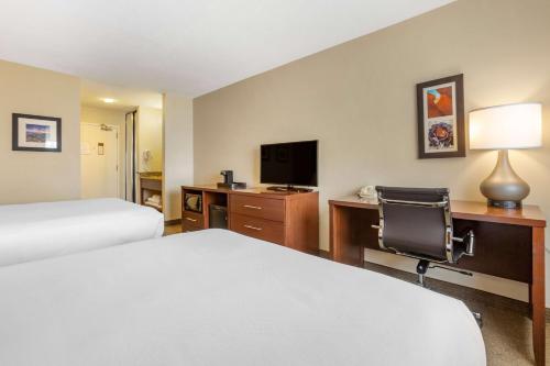 a hotel room with two beds and a desk with a television at Wingate by Wyndham Los Alamos in Los Alamos