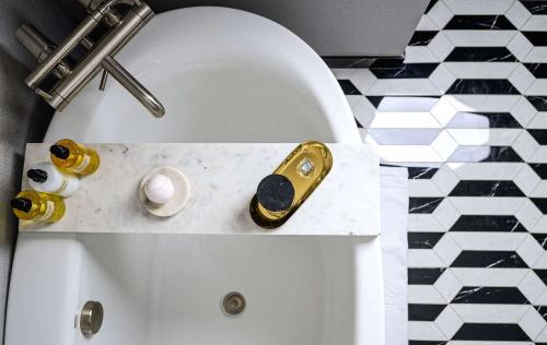 a white bath tub with a gold harmonica in a bathroom at Daxton Hotel Birmingham, Curio Collection by Hilton in Birmingham