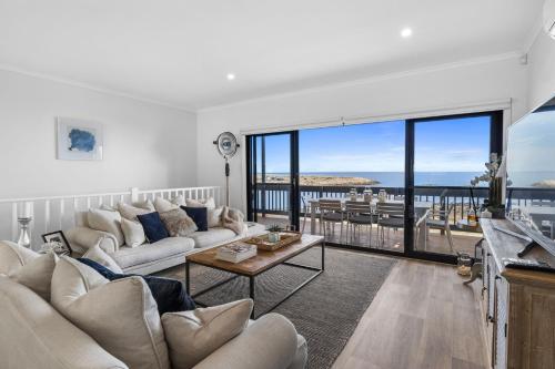 a living room with white furniture and a large window at Shoreline Escape in Wirrina Cove