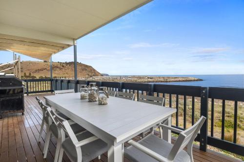 a white table and chairs on a deck with a view of the ocean at Shoreline Escape in Wirrina Cove