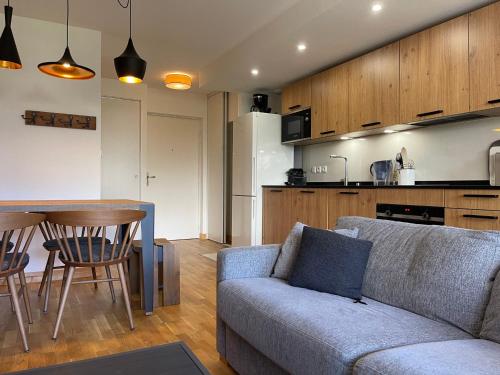 un salon avec un canapé et une table et une cuisine dans l'établissement Bel appartement, résidence neuve, parking, wifi - FR-1-624-171, à Samoëns