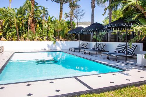 a swimming pool with chairs and umbrellas in a resort at Coco Queen in Paarl