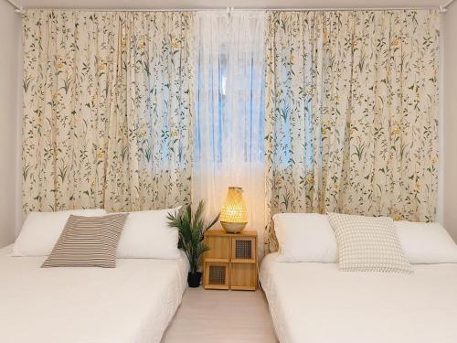 a bedroom with two beds and a window with curtains at Sha lala stay in Seoul