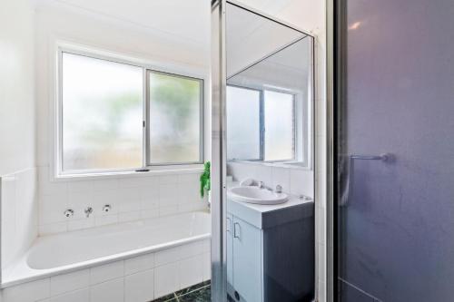 a bathroom with a tub and a sink and a mirror at Light and Bright at Maloneys in Maloney's Beach