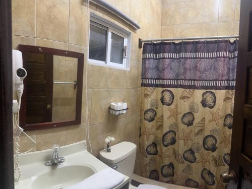 a bathroom with a sink and a toilet and a shower curtain at SKY INN in Caye Caulker