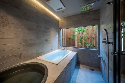 Un baño grande con bañera y ventana. en Tokisora Machiya House, en Kanazawa