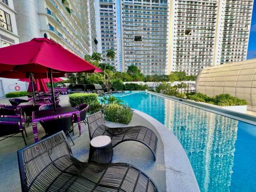 a swimming pool with chairs and tables and a red umbrella at Novotel Residential Tower at Acqua Private Residences Mandaluyong - Makati in Manila