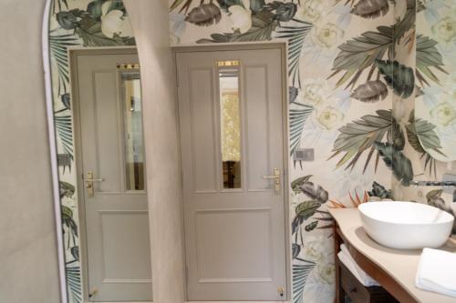 a bathroom with a white door and floral wallpaper at Girisadan Boutique Stay in Jaipur