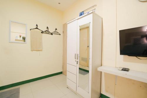 a room with a tv and a white cabinet at Le Paris Syariah Residence in Tangerang