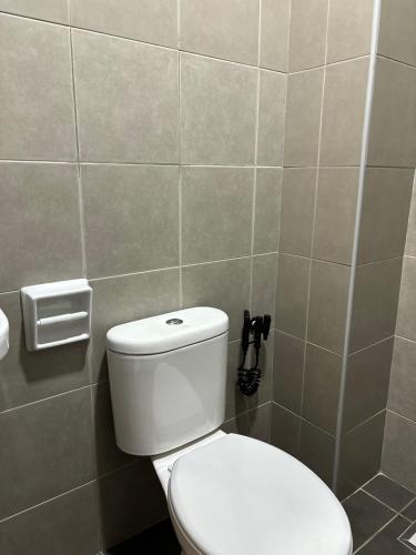 a bathroom with a toilet and a tiled wall at Dreamstays near UTM JPO Temple Senai Airport in Skudai
