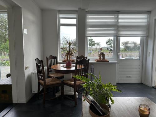 a dining room with a table and chairs and windows at Het Tinkerparadijs, paarden, rust en ruimte. in Burgh Haamstede