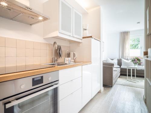 a kitchen with white appliances and a living room at UNS MUUSLOCK in Ahrenshoop