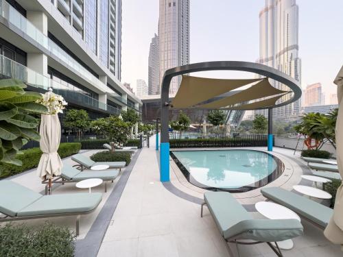 a swimming pool on the roof of a building with lounge chairs at Luxury 1BR 5min to Dubai Mall Burj Khalifa View from pool in Dubai